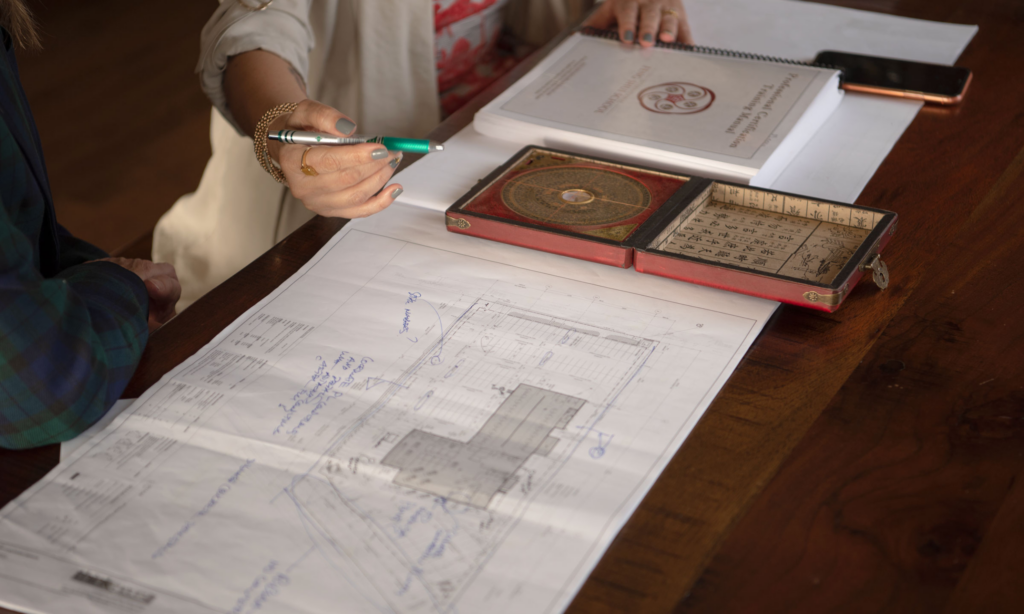 Meena with a house plan on the desk