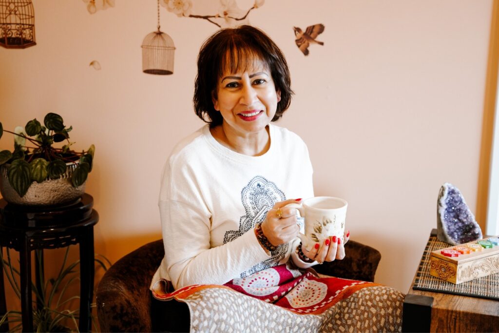 Meena is sitting in her living room with a cup of tea