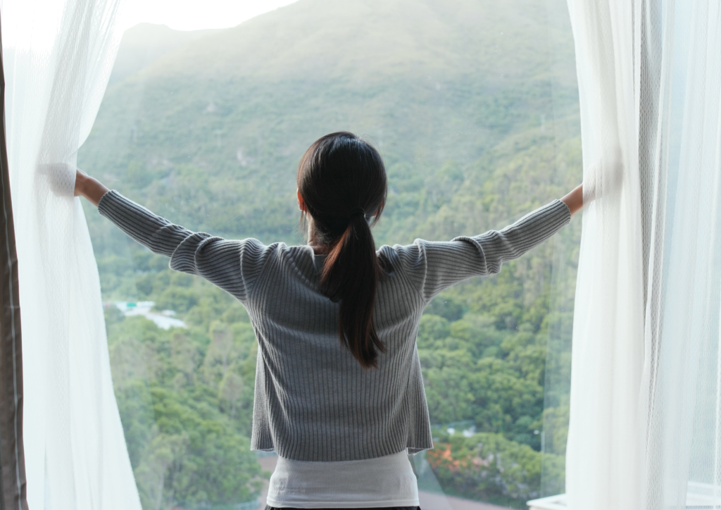 A woman is opening the blinds